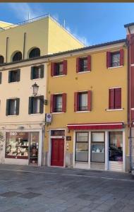 a yellow building with red windows on a street at Al Sagraeto in Chioggia