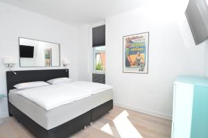 a white bedroom with a bed and a tv at Ostseeresidenz Sassnitz - Penthouse 20 mit Sauna, Balkon, Meerblick in Sassnitz