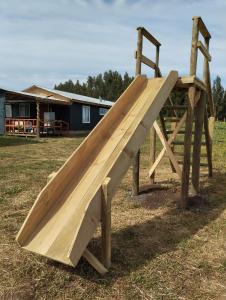 a wooden slide in a field with a house at Cabañas encanto de Chovellen in Pelluhue
