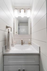 a white bathroom with a sink and a mirror at Ocean Block Condo 100 Steps From the Beach in Ocean City