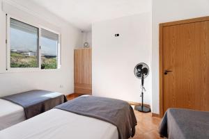 1 dormitorio con 2 camas, ventilador y ventana en La Cuadra de Juan, en La Frontera