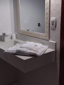 a white bathroom with a sink and a mirror at Chalé Estância da Pinha seu Refúgio na Montanha in Santo Antônio do Pinhal