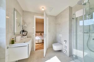 La salle de bains est pourvue d'une douche, d'un lavabo et de toilettes. dans l'établissement Hermitage Vital Hotel, à Maria Wörth
