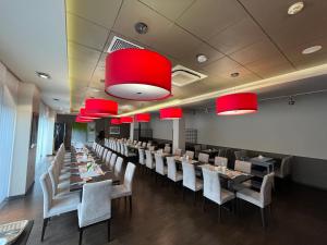 una sala da pranzo con tavoli, sedie e lampadari a braccio rossi di Iness Hotel a Łódź