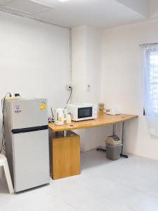 a kitchen with a refrigerator and a desk with a microwave at TRANSIT Donmueang Airport HOSTEL in Thung Si Kan