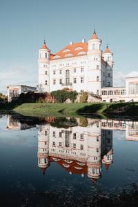 a large white castle with its reflection in the water at Pałac Wojanów in Wojanów