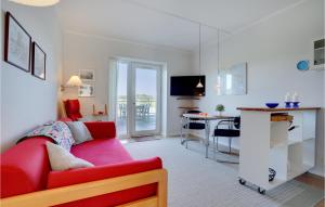1 Bedroom Gorgeous Apartment In Grsten في جراستين: غرفة معيشة مع أريكة حمراء ومطبخ