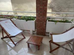 two chairs and a bench on a balcony with potted plants at Hôtel Saïfee International in Toliara