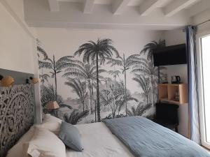 ein Schlafzimmer mit einem Wandbild von Palmen in der Unterkunft La Clairière du Seignanx in Saint-Martin-de-Seignanx