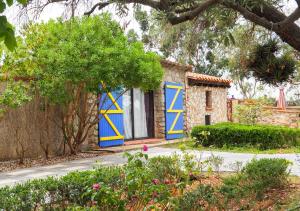 a house with blue and yellow doors in a garden at gîte mas d'en pachette in Le Boulou