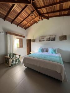 um quarto com uma cama grande e uma cadeira em La Bella Suítes em Ilhabela