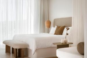 a white bedroom with a white bed and a chair at Mykonos Flow - Super Paradise in Super Paradise Beach