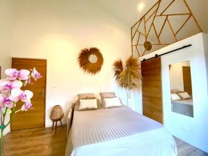 een slaapkamer met een bed en een spiegel en bloemen bij Villa L’Eden Zen face à l océan in Saint-Pierre