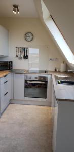 a kitchen with white cabinets and a clock on the wall at Highland Glen Lodges in Rogart