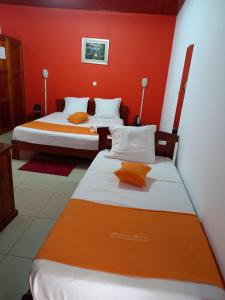 two beds in a room with red walls at Hôtel Saïfee International in Toliara