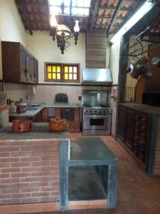 a large kitchen with a stove and a brick floor at Hospedagem para grupos in Piedade