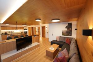 a living room with a large couch and a kitchen at Astergut Boutique Apartment in Saalbach Hinterglemm