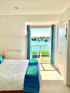 een slaapkamer met een bed en een groot raam bij Spinnaker Lodge · Cotswolds Lakeside Home in South Cerney