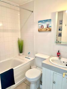 a bathroom with a toilet and a tub and a sink at Spinnaker Lodge · Cotswolds Lakeside Home in South Cerney