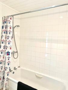 baño de azulejos blancos con bañera y cortina de ducha en Spinnaker Lodge · Cotswolds Lakeside Home, en South Cerney