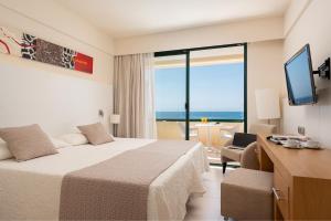 a hotel room with a bed and a view of the ocean at Welikehotel Marfil Playa in Sa Coma
