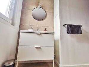 een badkamer met een witte wastafel en een spiegel bij Le Contemporain (Centre - Gare - Commerces) in Lens