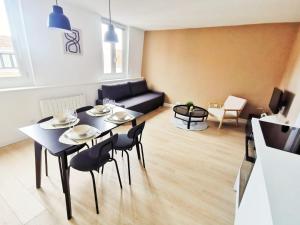 ein Wohnzimmer mit einem Tisch, Stühlen und einem Sofa in der Unterkunft Le Contemporain (Centre - Gare - Commerces) in Lens