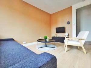 ein Wohnzimmer mit einem Sofa, einem Tisch und einem TV in der Unterkunft Le Contemporain (Centre - Gare - Commerces) in Lens
