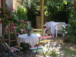 a garden with a table and chairs and flowers at Chambres D'Hôtes Des 3 Rois in Verdun-sur-Meuse