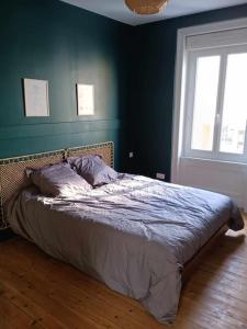 a bed in a bedroom with a blue wall at Maison de ville quartier Pasteur in Cherbourg en Cotentin