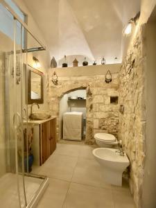 a stone bathroom with a shower and a toilet and a sink at Casa Tua - Sea View Chianca in Vieste