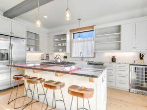 a kitchen with white cabinets and a counter with stools at GARDENS OF BARONS CREEK UNIT A in Fredericksburg