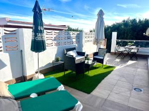 un patio con sillas y sombrillas en el balcón en Casa Carmen Ático Primera linea de playa en Málaga