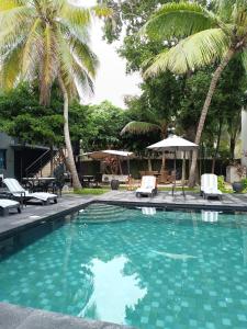 una piscina con palmeras, sillas y sombrilla en Grand City Hotel Cancun, en Cancún