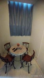 een eettafel met 4 stoelen en een raam bij Apartamento central particular in Lavras