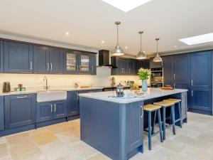 a kitchen with blue cabinets and a large island at 6 Bed in Blandford Forum 80549 in Milborne Saint Andrew