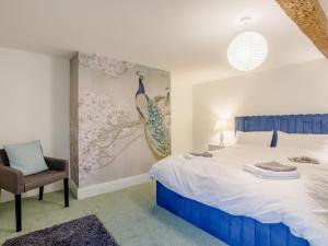 a bedroom with a blue and white bed and a chair at 6 Bed in Blandford Forum 80549 in Milborne Saint Andrew