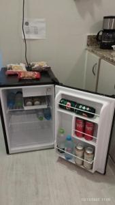 a small refrigerator with its door open in a kitchen at Apartamento central particular in Lavras
