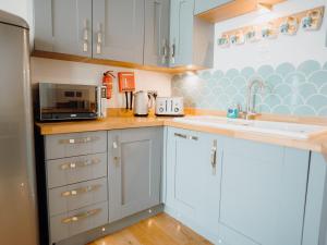 een keuken met witte kasten, een wastafel en een magnetron bij 2 Bed in Tenby FB285 in Tenby
