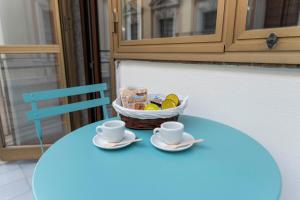 una mesa azul con dos tazas y una cesta de fruta en Calypsosuite en Salerno