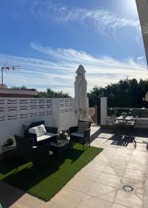 un patio con sillas y una sombrilla en el techo en Casa Carmen Ático Primera linea de playa en Málaga