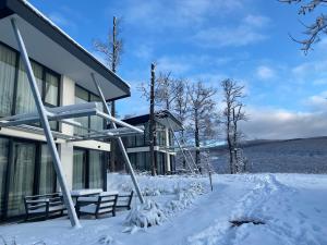 ein Haus mit Schnee auf dem Boden davor in der Unterkunft Hotel Ózon & Luxury Villas in Mátraháza