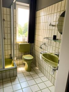 ein Badezimmer mit grünem WC und Waschbecken in der Unterkunft Apt Prinz Ernst August - Zimmerprinzen - Zentral in Oldenburg