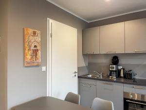 eine Küche mit weißen Schränken und einem Tisch mit Stühlen in der Unterkunft Apartment Prinzessin Eloise - Zimmerprinzen in Oldenburg + 4 Fotos