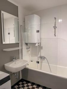 ein weißes Bad mit einem Waschbecken und einer Dusche in der Unterkunft Apartment Prinz Leopold - Zentral - Zimmerprinzen in Oldenburg
