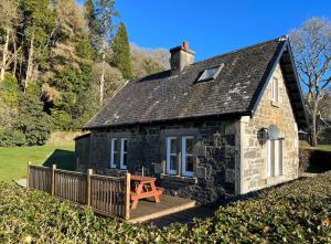 una pequeña casa de piedra con un banco delante en The Lodge, en Lochgilphead