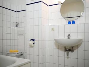 a bathroom with a sink and a mirror and a toilet at Gästehaus - Residenz Kormoran in Prerow