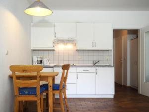 cocina con armarios blancos, mesa de madera y silla en Gästehaus - Residenz Kormoran, en Prerow