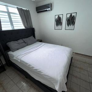 a bedroom with a bed with white sheets and a window at Studio21-A Centric Comfort Apartment in Bayamon