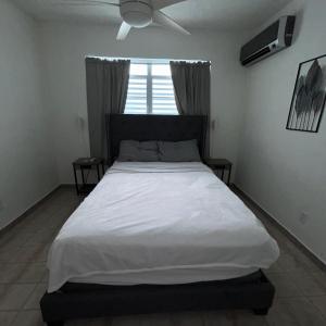 ein großes Bett in einem Schlafzimmer mit Deckenventilator in der Unterkunft Studio21-A Centric Comfort Apartment in Bayamon